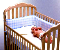 A baby in a smart wooden crib.