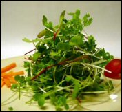 A small heap of microgreens in a glass bowl.